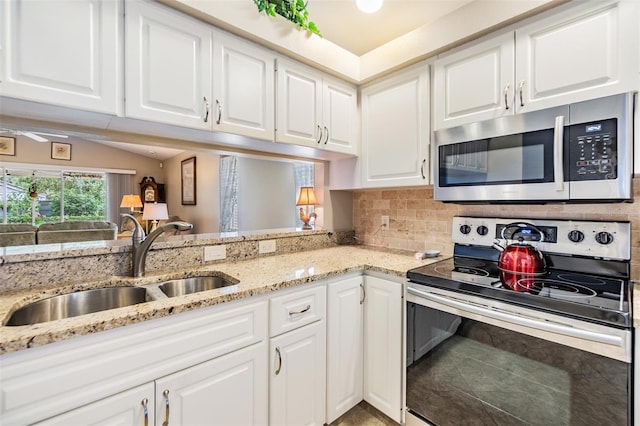 kitchen with light stone countertops, sink, white cabinets, and stainless steel appliances