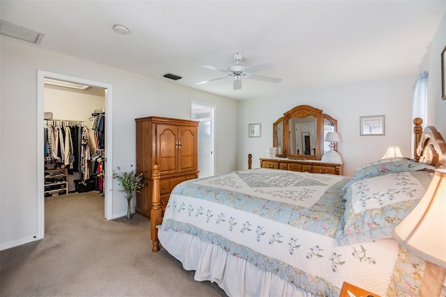 bedroom featuring a walk in closet, ceiling fan, a closet, and light carpet