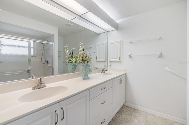 bathroom with tile patterned floors, vanity, a shower with shower door, and a textured ceiling