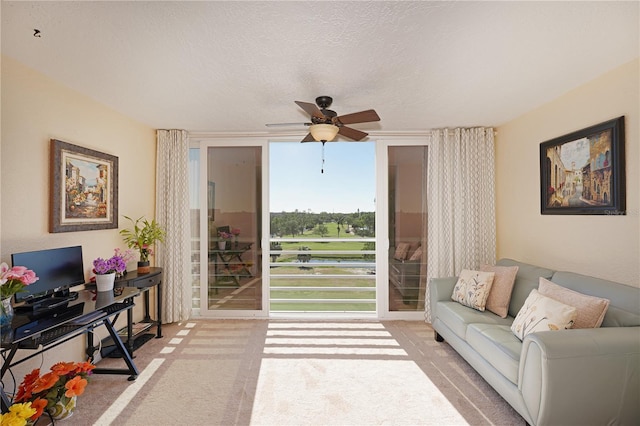 living room with ceiling fan, light colored carpet, and a textured ceiling