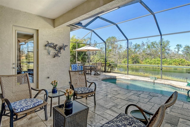 view of pool featuring glass enclosure, a patio area, and a water view