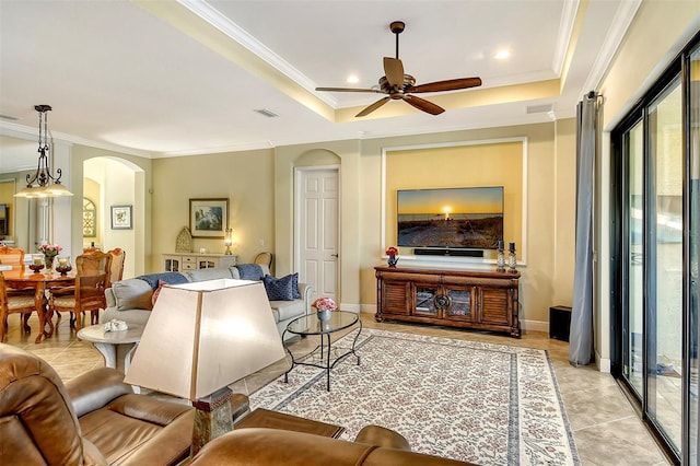 tiled living room featuring ceiling fan, a raised ceiling, and ornamental molding