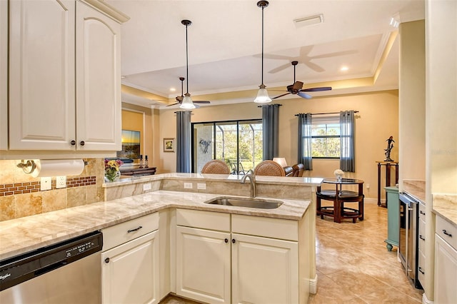 kitchen featuring dishwasher, sink, tasteful backsplash, kitchen peninsula, and a tray ceiling