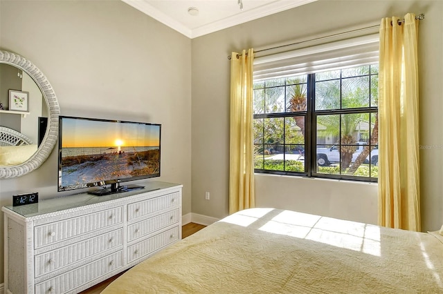 bedroom featuring multiple windows, hardwood / wood-style floors, and ornamental molding