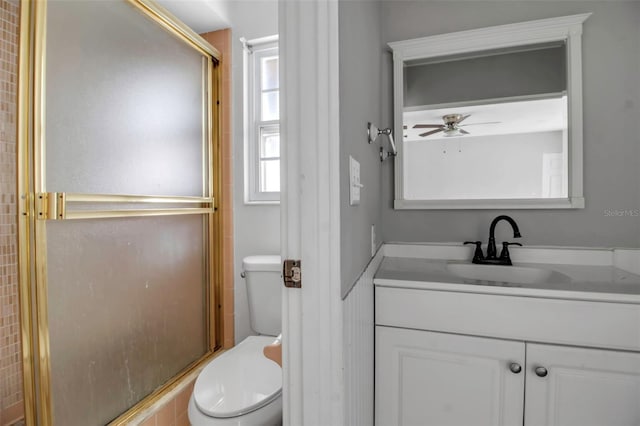 bathroom featuring vanity, a shower with door, toilet, and ceiling fan