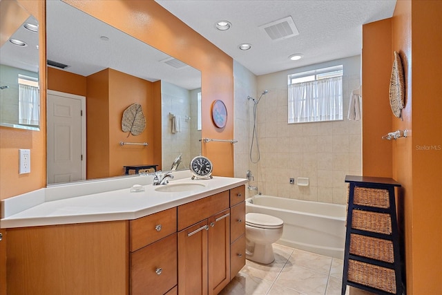 full bathroom with vanity, tiled shower / bath, tile patterned flooring, toilet, and a textured ceiling