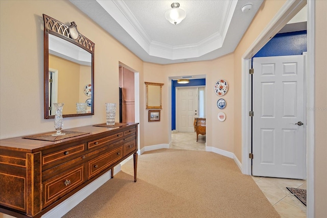 hallway with a raised ceiling, light carpet, a textured ceiling, and ornamental molding