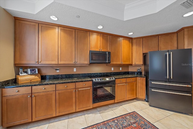 kitchen with light tile patterned flooring, a textured ceiling, dark stone counters, and black appliances