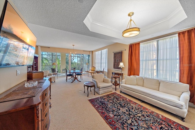 carpeted living room with ornamental molding, a textured ceiling, a raised ceiling, and a notable chandelier