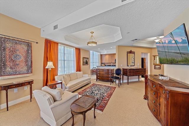 carpeted living room featuring a textured ceiling, a tray ceiling, and ornamental molding