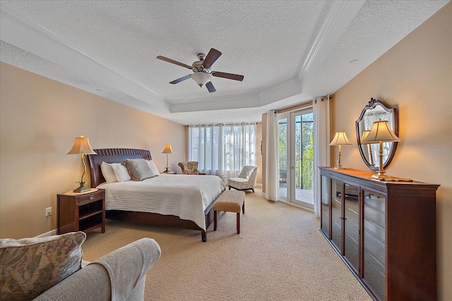 bedroom featuring access to exterior, light carpet, a tray ceiling, and ceiling fan