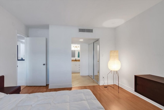 bedroom with ensuite bath, sink, and light wood-type flooring