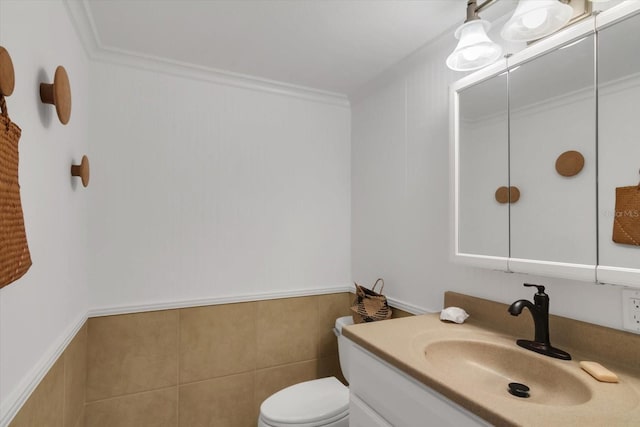 bathroom featuring vanity, toilet, ornamental molding, and tile walls