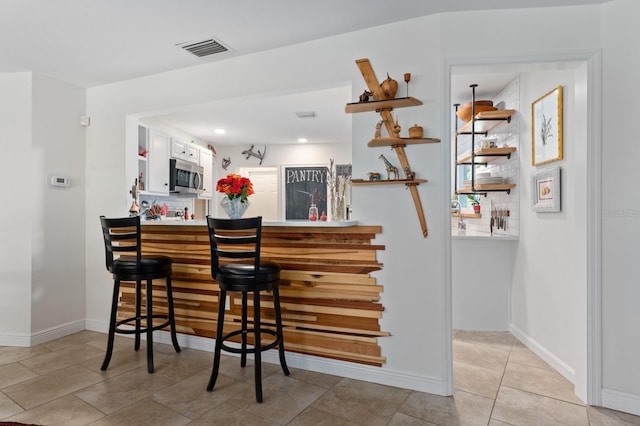 bar featuring tasteful backsplash and light tile patterned flooring