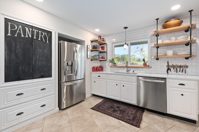 kitchen featuring white cabinetry, sink, stainless steel appliances, pendant lighting, and decorative backsplash