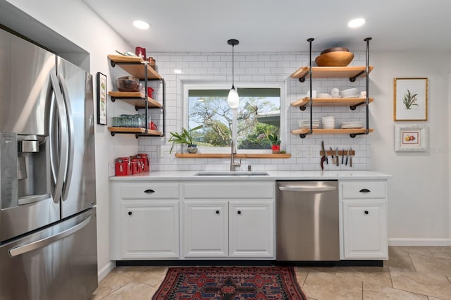 kitchen with white cabinets, decorative backsplash, hanging light fixtures, and appliances with stainless steel finishes