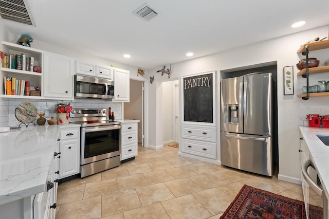 kitchen with light stone countertops, decorative backsplash, stainless steel appliances, and white cabinetry