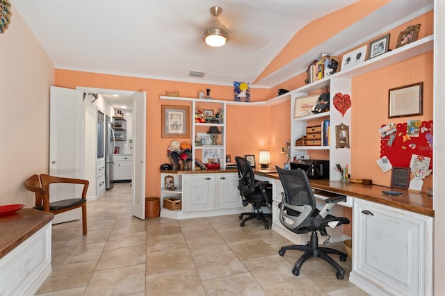 office space featuring ceiling fan, built in desk, light tile patterned floors, and vaulted ceiling