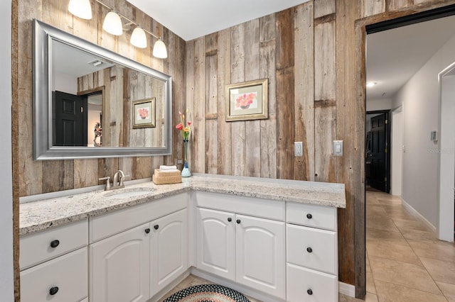 bathroom featuring tile patterned flooring, vanity, and wood walls