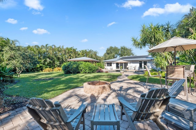 wooden terrace featuring an outdoor fire pit, a patio area, and a lawn