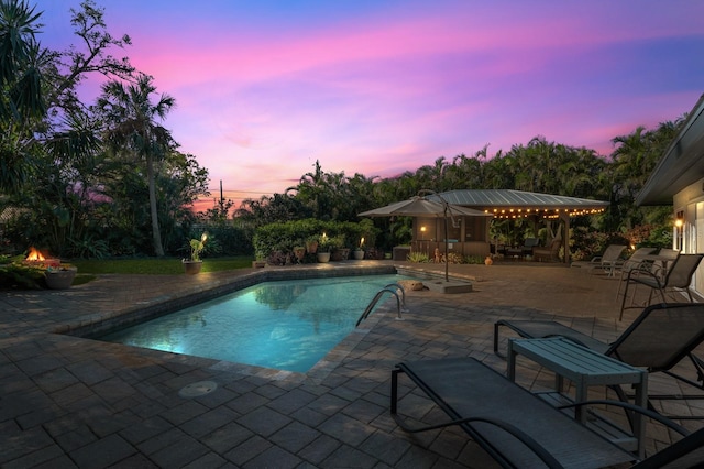 pool at dusk featuring a patio area