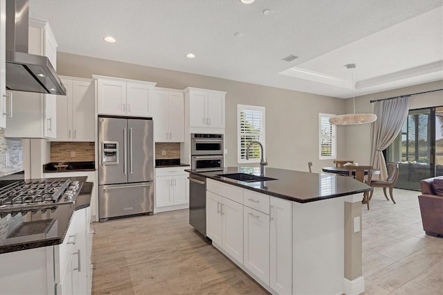 kitchen featuring sink, white cabinets, wall chimney range hood, and appliances with stainless steel finishes