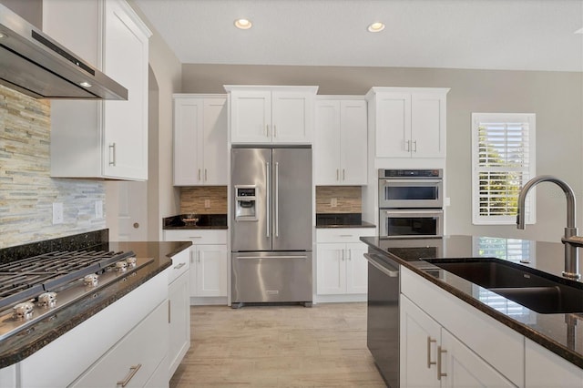 kitchen featuring decorative backsplash, sink, stainless steel appliances, and wall chimney range hood