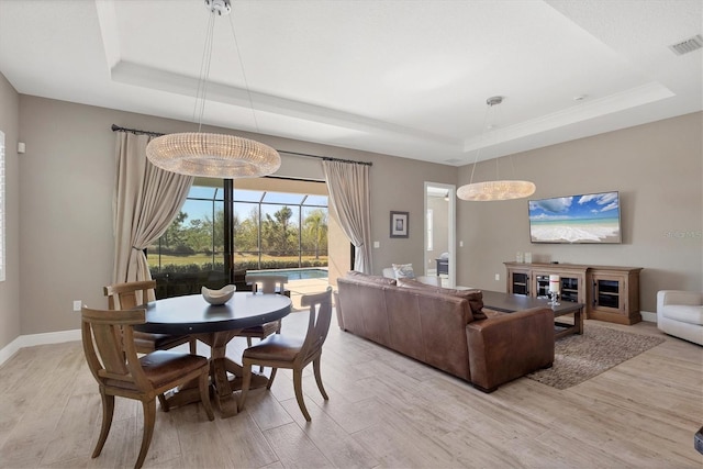 dining room featuring light wood-type flooring and a tray ceiling