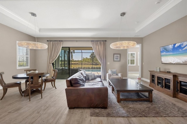 living room featuring light hardwood / wood-style floors, a tray ceiling, and a chandelier