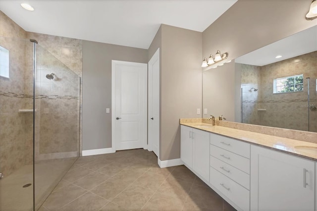 bathroom with tile patterned flooring, vanity, and a tile shower