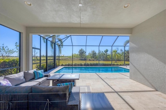 view of pool featuring glass enclosure, an outdoor hangout area, and a patio