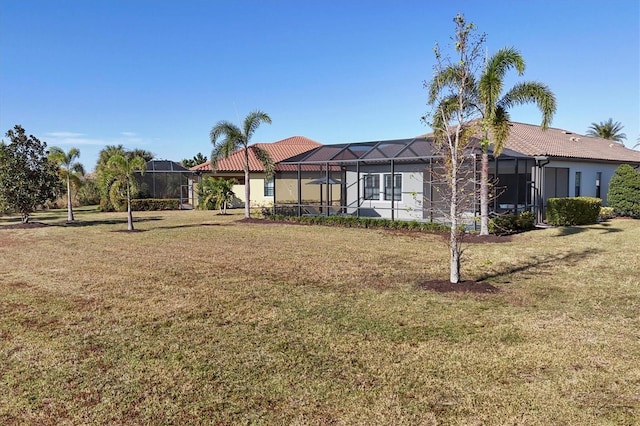 rear view of house with a lanai and a lawn