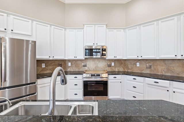 kitchen with sink, dark stone counters, decorative backsplash, white cabinets, and appliances with stainless steel finishes