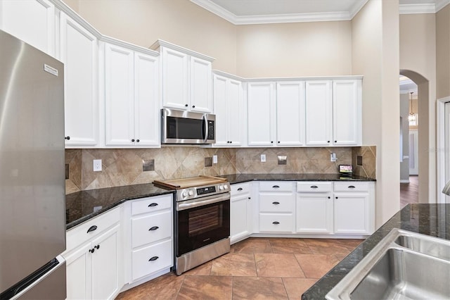 kitchen featuring white cabinets, appliances with stainless steel finishes, backsplash, and dark stone counters