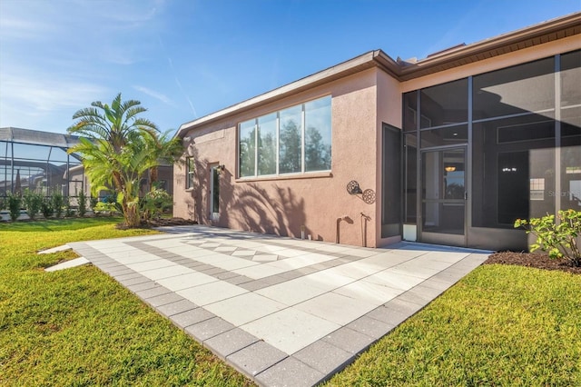 rear view of house with a lanai, a yard, and a patio