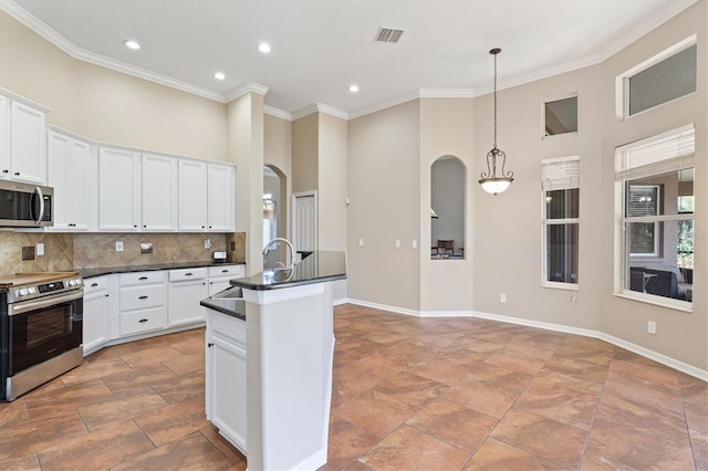 kitchen featuring white cabinets, hanging light fixtures, appliances with stainless steel finishes, and tasteful backsplash