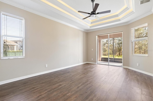 empty room with ceiling fan, dark hardwood / wood-style floors, ornamental molding, and a tray ceiling