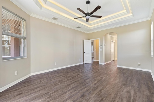 unfurnished room featuring a raised ceiling, dark wood-type flooring, and ornamental molding