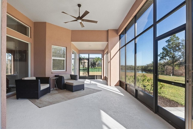 sunroom / solarium featuring ceiling fan and a water view