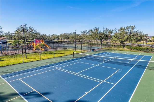 view of tennis court featuring a playground