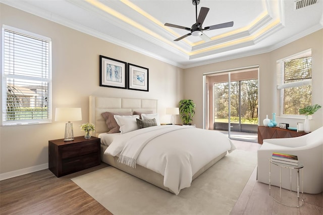 bedroom featuring ceiling fan, access to exterior, crown molding, and a tray ceiling