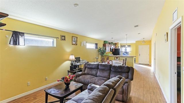 living room with a textured ceiling, light hardwood / wood-style floors, and vaulted ceiling