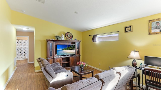 living room featuring light hardwood / wood-style floors and vaulted ceiling