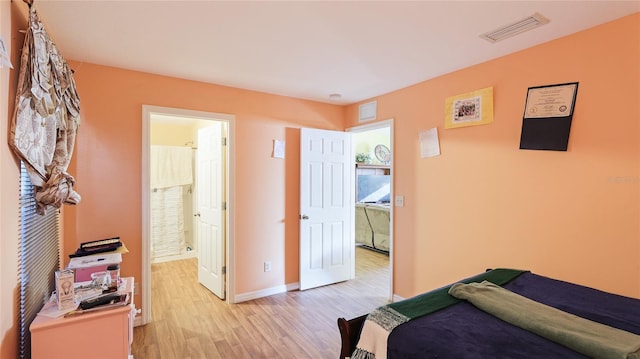 bedroom featuring light wood-type flooring and ensuite bathroom