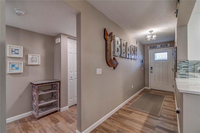 foyer featuring light hardwood / wood-style floors, a textured ceiling, and a notable chandelier