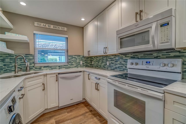 kitchen with light wood-type flooring, white appliances, sink, white cabinets, and washer / dryer