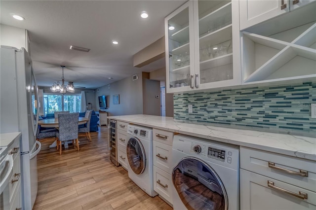 washroom with an inviting chandelier, washer / dryer, wine cooler, and light hardwood / wood-style flooring