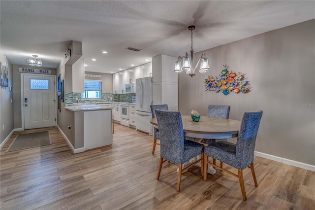 dining area with a textured ceiling and light hardwood / wood-style flooring