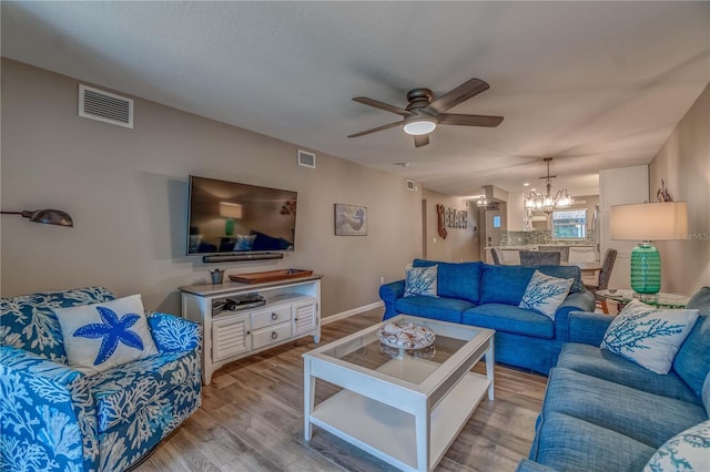 living room with light hardwood / wood-style flooring and ceiling fan with notable chandelier