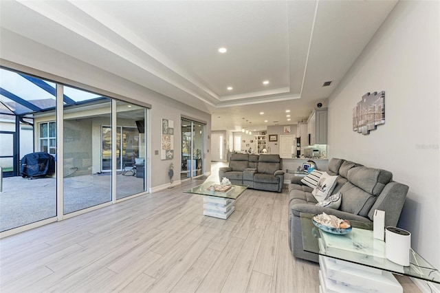 living room featuring light wood-type flooring and a tray ceiling